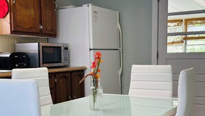 A modern kitchen with white appliances, a glass dining table, and white chairs. - Pet friendly Near Lake George and Saratoga (Corinth)