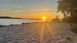 Une plage où le soleil se couche sur l’eau, une côte rocheuse et une balançoire.