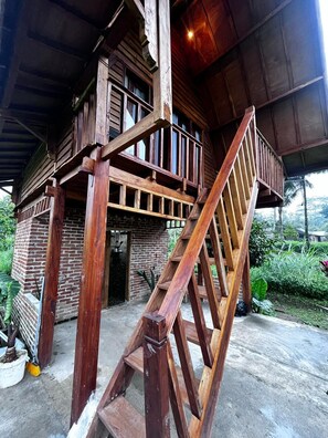 A wooden cabin with a wooden staircase leading to a balcony. - Tetebatu rice field bliss (West Nusa Tenggara)