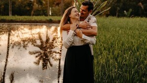 A couple embracing in a field with palm trees and a body of water in the background. - Tetebatu rice field bliss (West Nusa Tenggara)