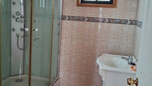 A bathroom with a glass-enclosed shower, a sink, and a window above the sink. - Hostal el Campito (San Antonio)