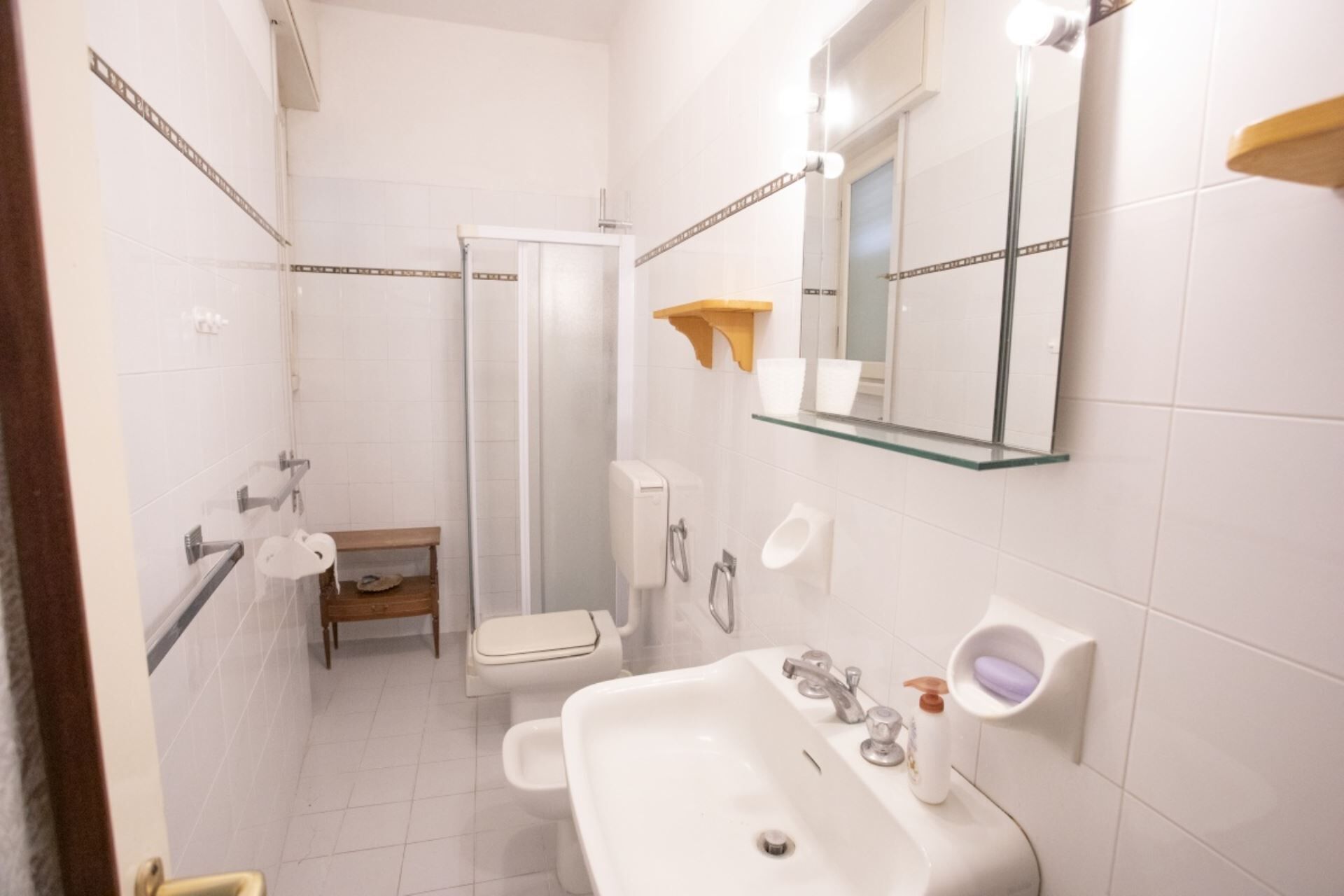 A bathroom with a shower, toilet, sink, and a mirror.