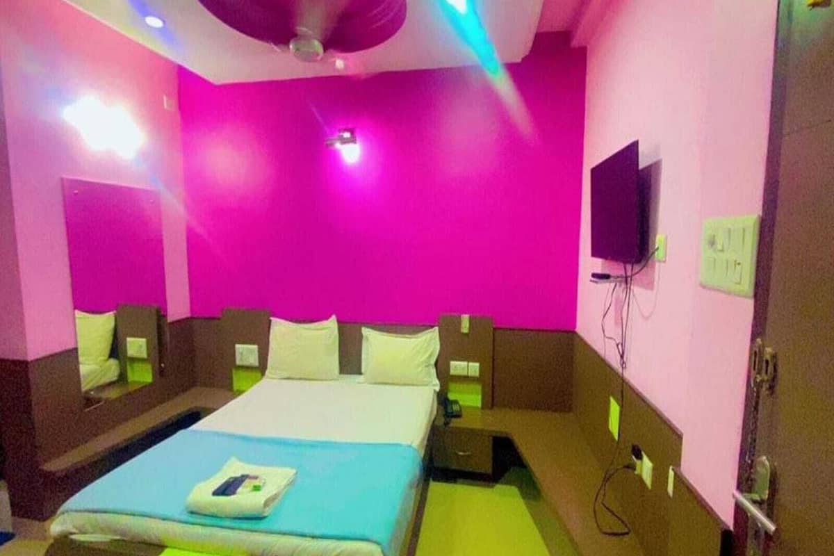 Una habitación de hotel muy colorida con cama, mesitas de noche, televisión y ventilador de techo.