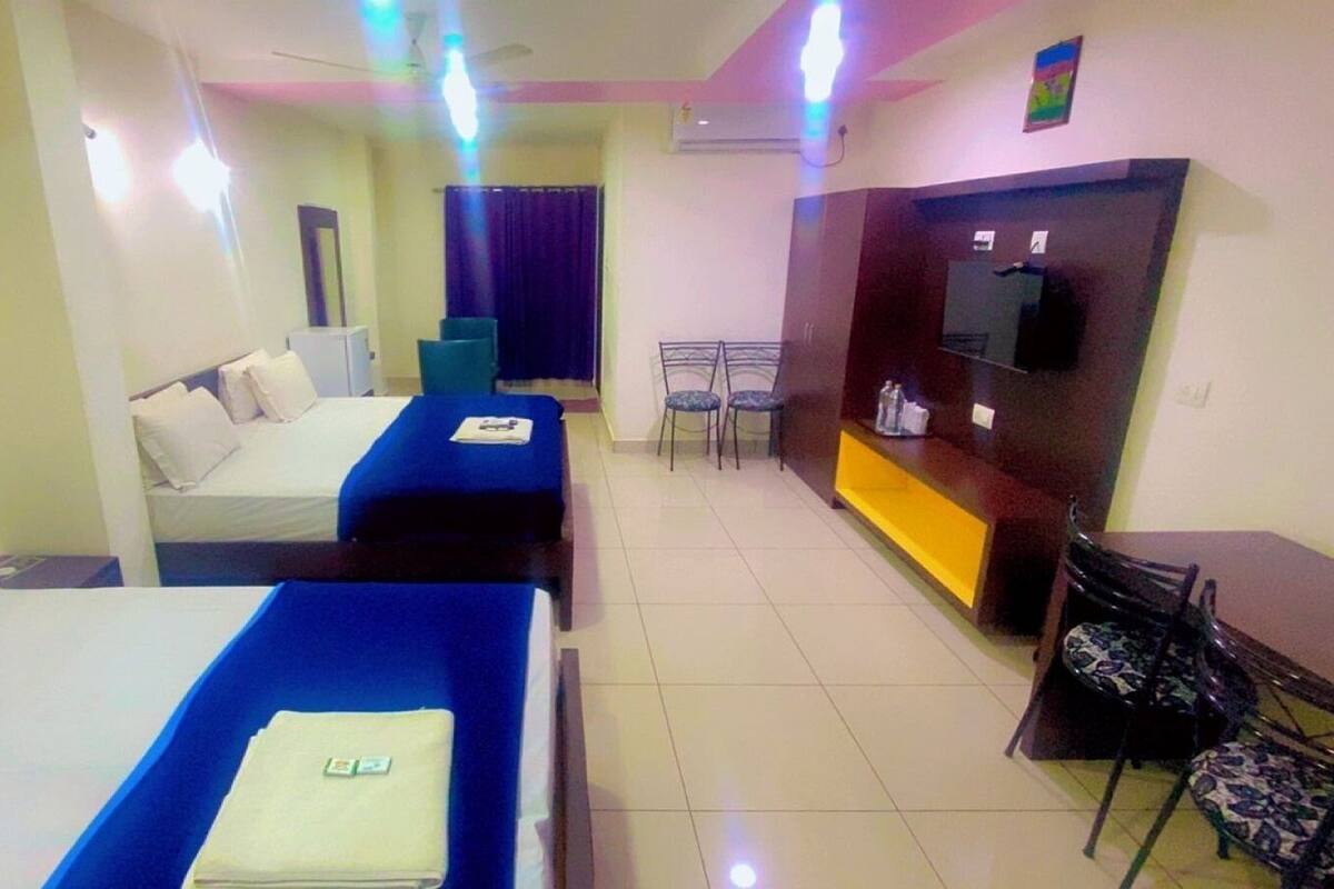 Habitación de hotel con dos camas, un escritorio, una silla, un televisor y un pequeño comedor.