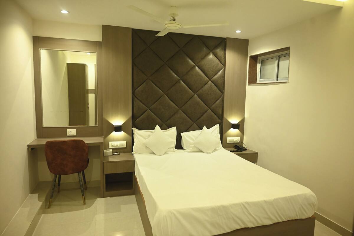 A modern bedroom with a large bed, a desk, a chair, and a ceiling fan.