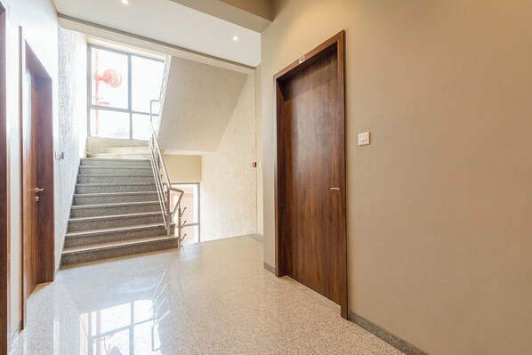 Un couloir avec une porte en bois, un escalier et un plancher de couleur claire.