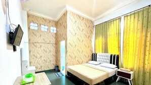 A hotel room with a bed, bedside table, and a TV mounted on the wall. - Yani Guesthouse (Bukittinggi)
