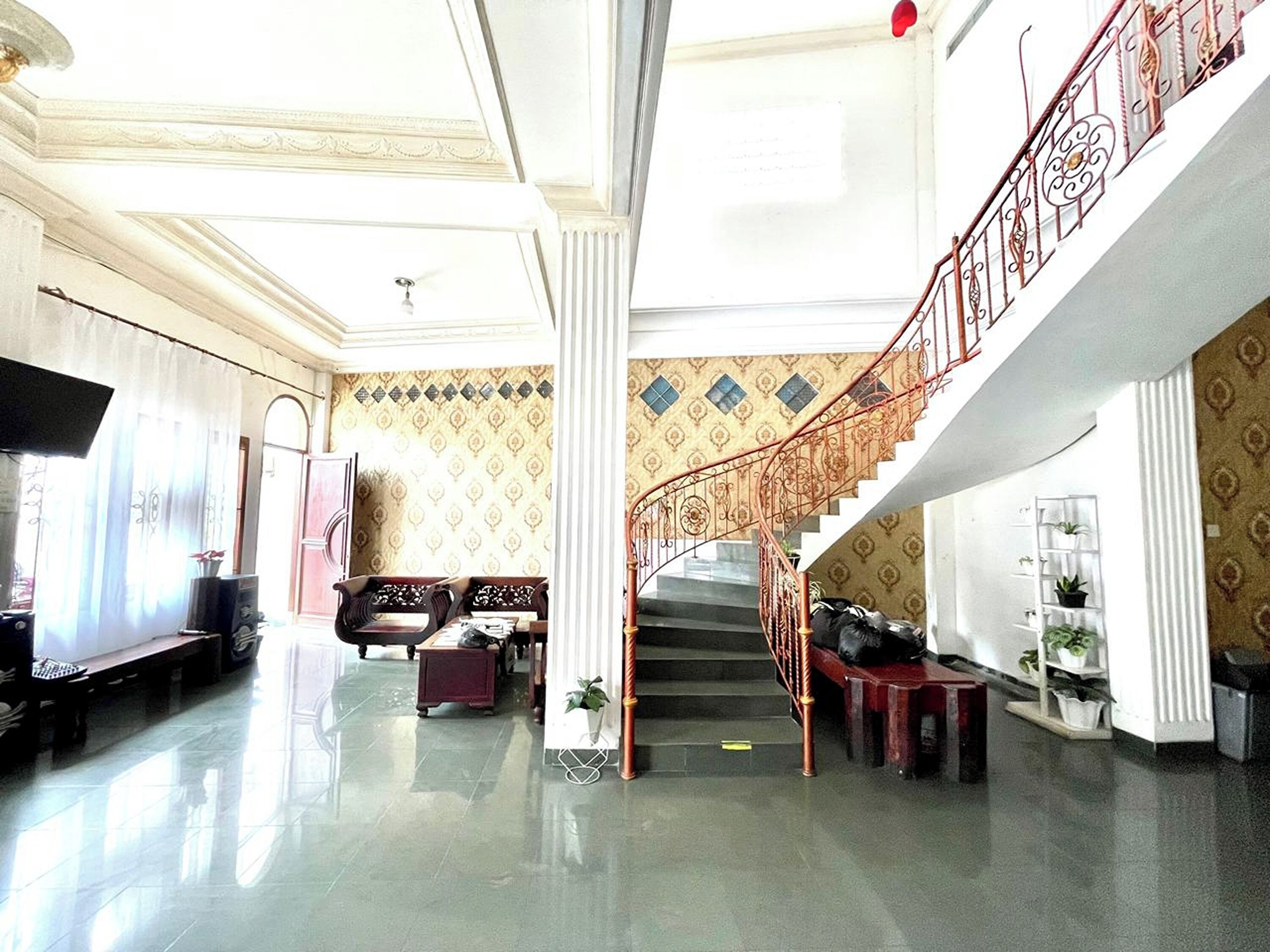 A spacious lobby with a grand staircase, a seating area with sofas, and a television.