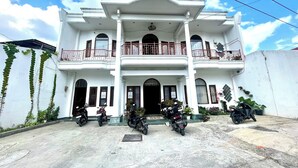 A two-story building with a balcony on the upper floor, a front entrance, and several parked motorcycles. - Yani Guesthouse (Bukittinggi)