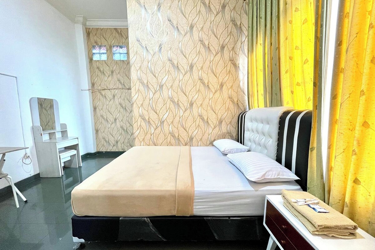 A hotel room with a bed, a desk, a chair, and a window with curtains.