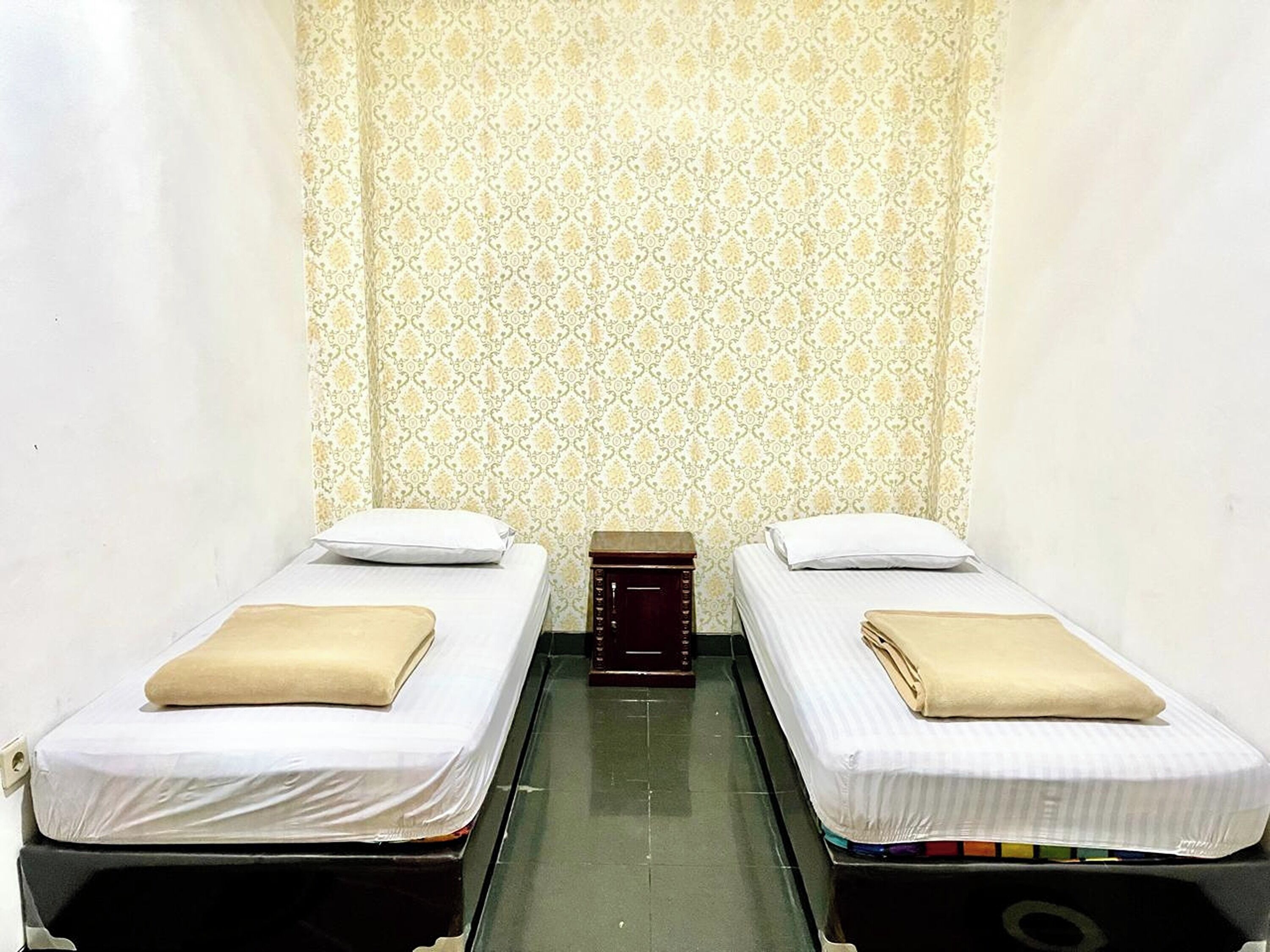 A room with two single beds, each with a pillow and a folded blanket.