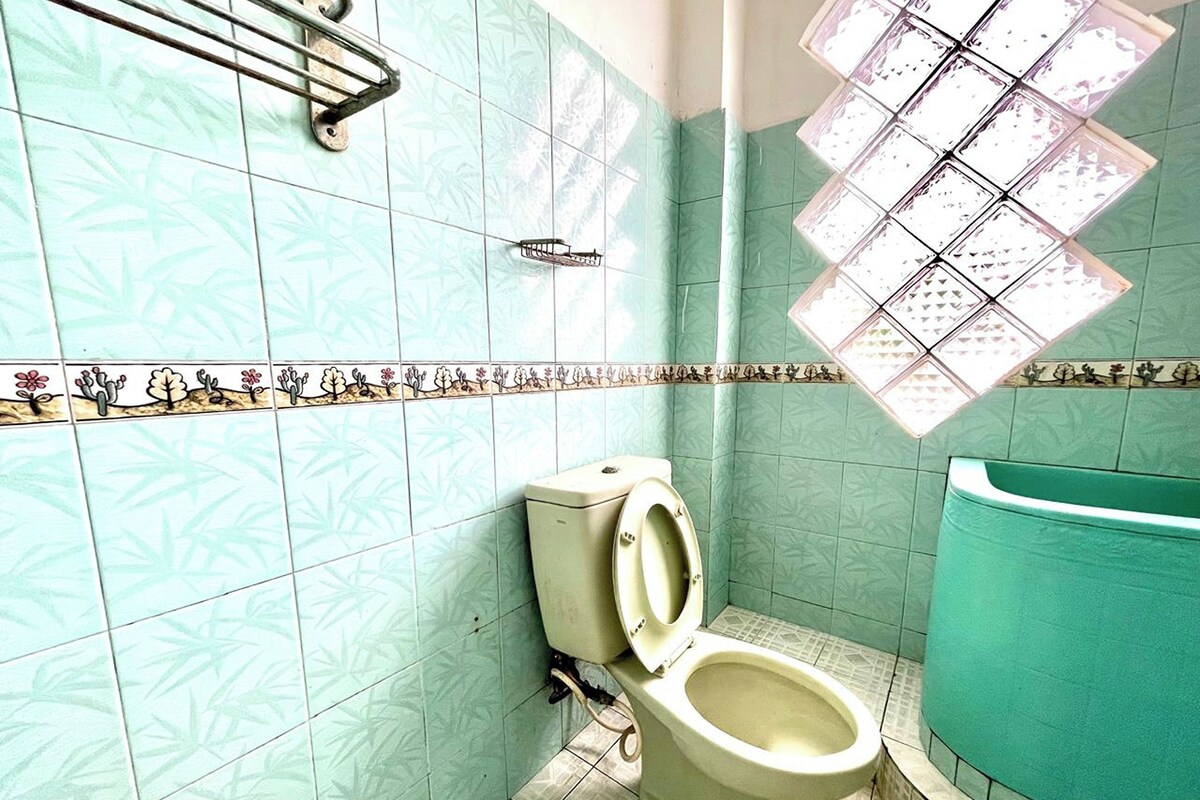 A bathroom with a toilet, a handrail, and a bathtub.