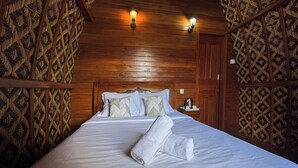 A neatly made bed with white linens and two rolled towels, a wooden headboard, and patterned wallpaper. - Green Lake Bali (Kintamani)