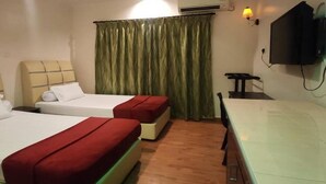 A hotel room with two beds, a desk, a television, and an air conditioning unit. - Darul Salam Inn (Kerteh)