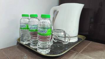 A tray with three bottles of water and a glass mug on a tiled surface.