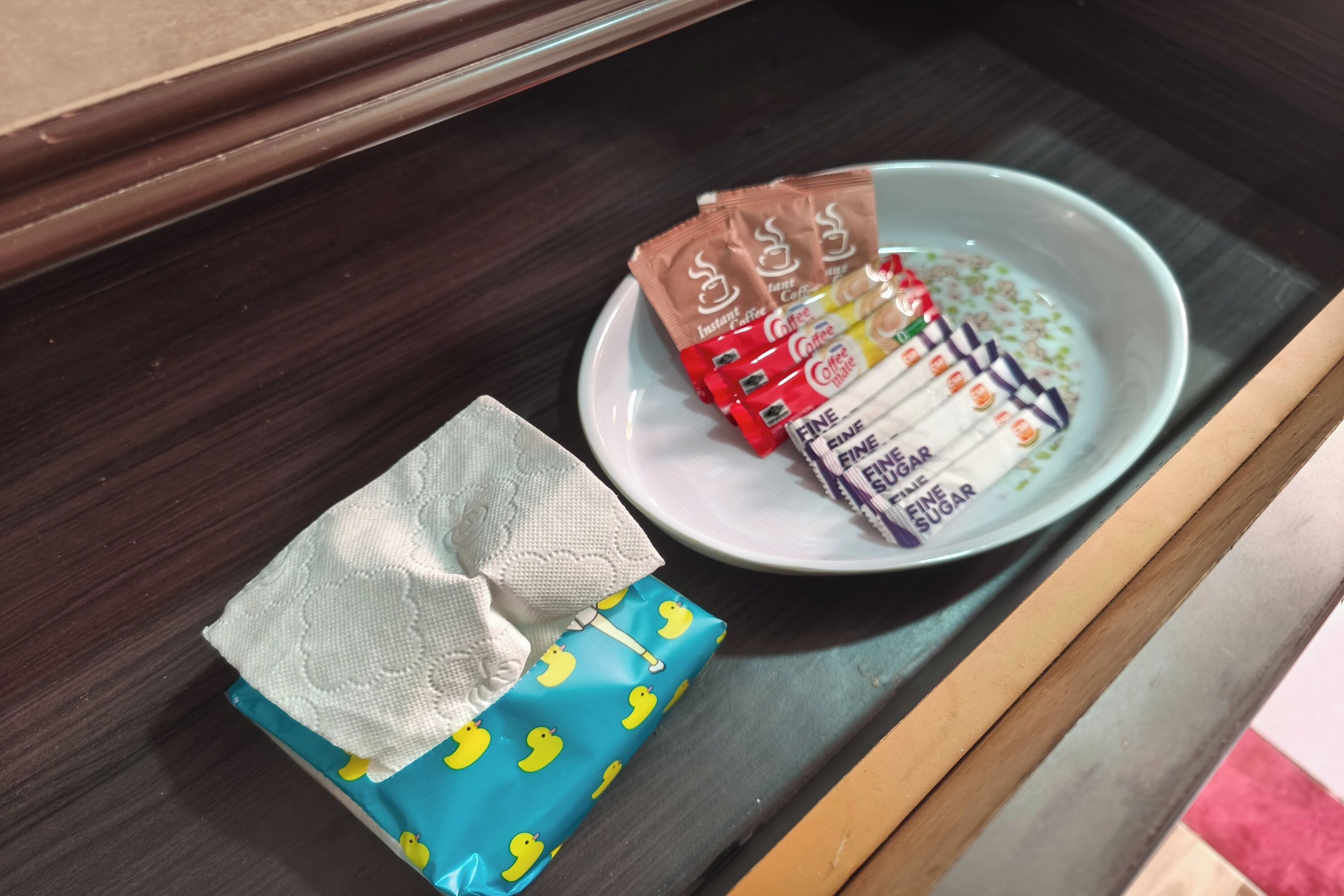 A plate with instant coffee packets and a wrapped gift on a table.