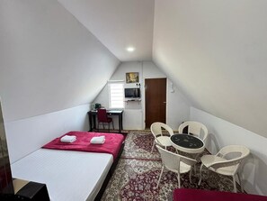 A small, compact room with a bed, a small table with chairs, a TV, and a door. - Darul Salam Dusun Resort & Waterpark (Kerteh)