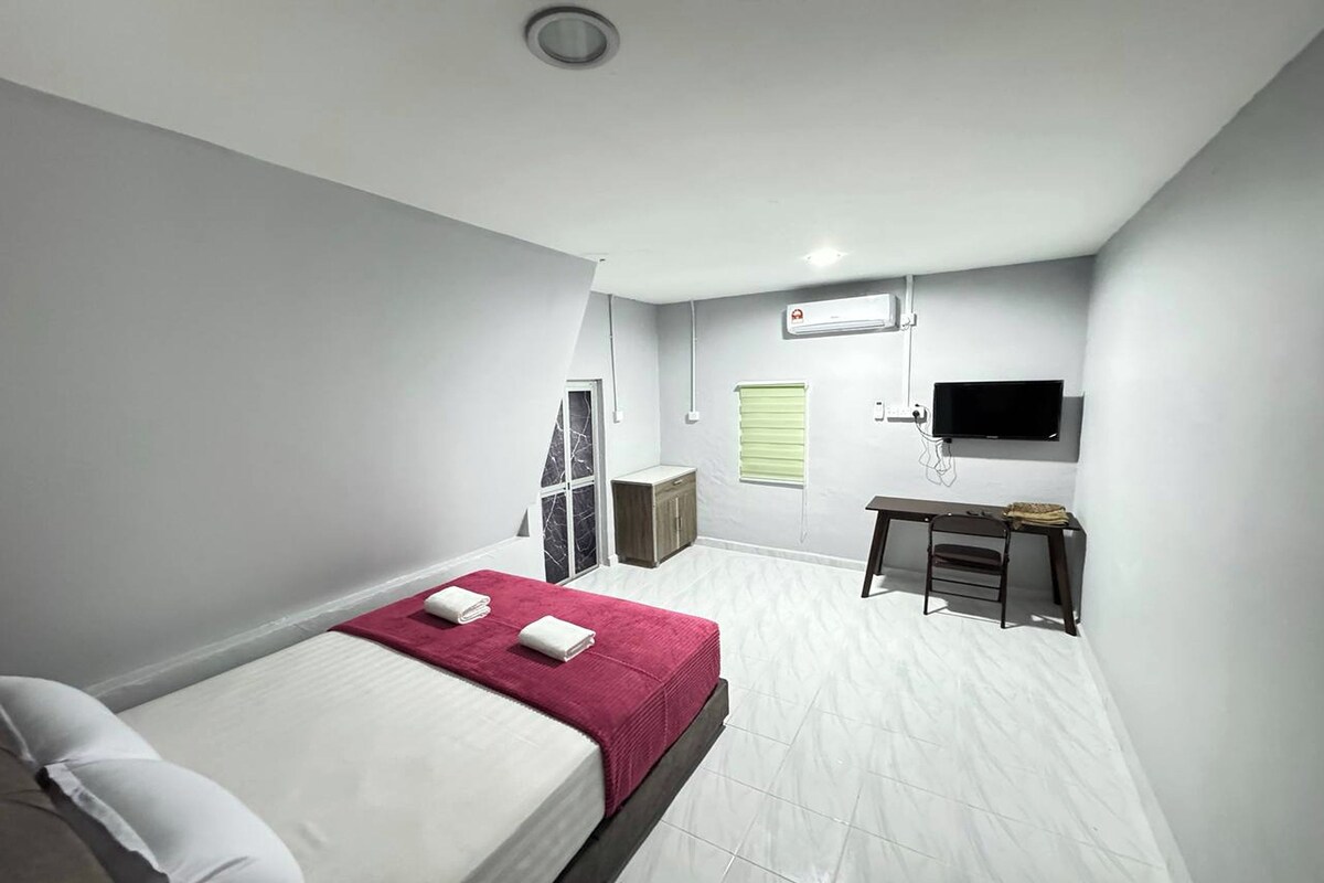 Una habitació d'hotel moderna amb llit, escriptori, cadira, televisió i finestra amb persianes.