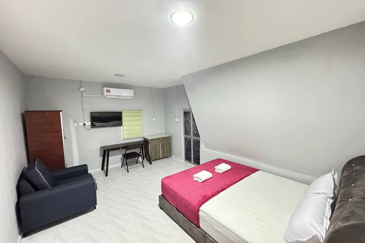 A compact hotel room with a bed, a desk, a chair, and a TV.