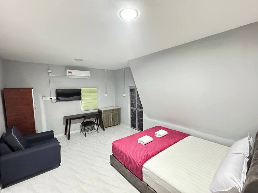 Una habitación de hotel pequeña con cama, escritorio, silla y televisor.