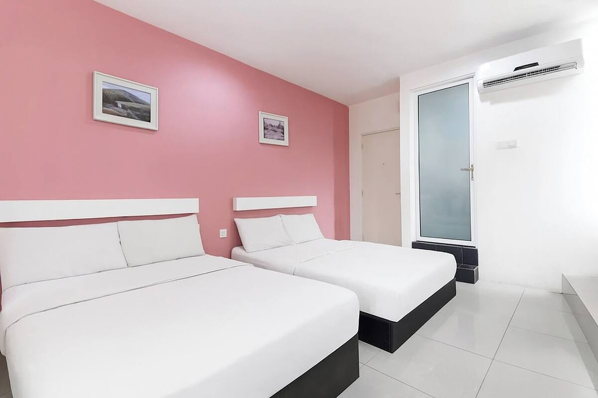 A room with two beds, pink walls, and a door with a frosted glass panel.
