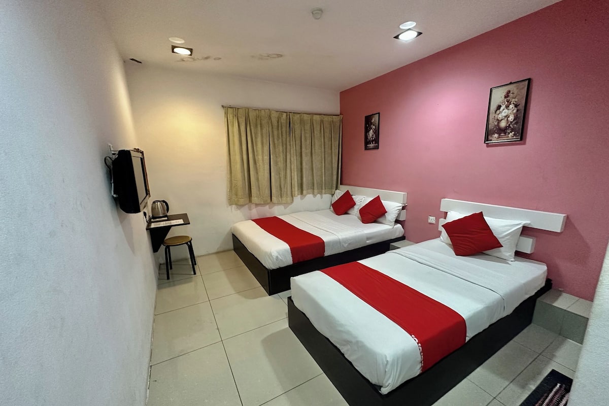 A hotel room with two beds, a desk, a chair, and a window with curtains.