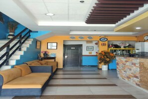 A modern lobby with a staircase, a reception desk, and a sofa area.