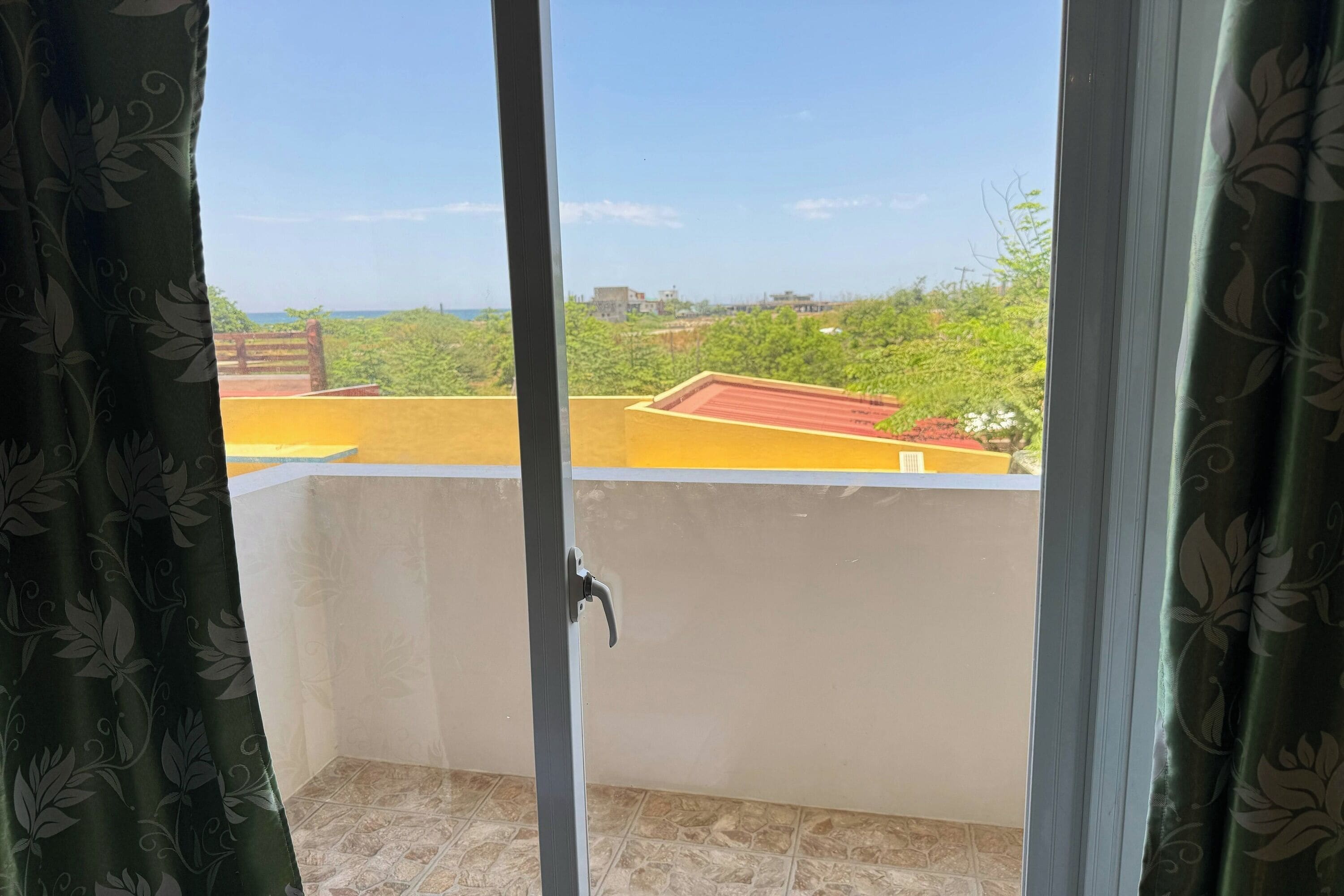 A balcony with a view of a green landscape and buildings.