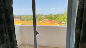 A balcony with a view of a green landscape and buildings.