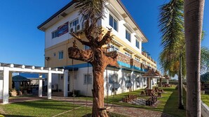 A hotel with a large tree sculpture in the courtyard, outdoor seating, and a clear blue sky.