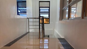 A corridor with a polished floor, a metal railing, and a window with multiple panes. - White-Beach Hideaway Resort Puerto Galera (Puerto Galera)