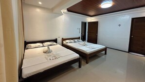 A hotel room with two beds, wooden headboards, white bedding, and a wooden ceiling with recessed lighting. - White-Beach Hideaway Resort Puerto Galera (Puerto Galera)