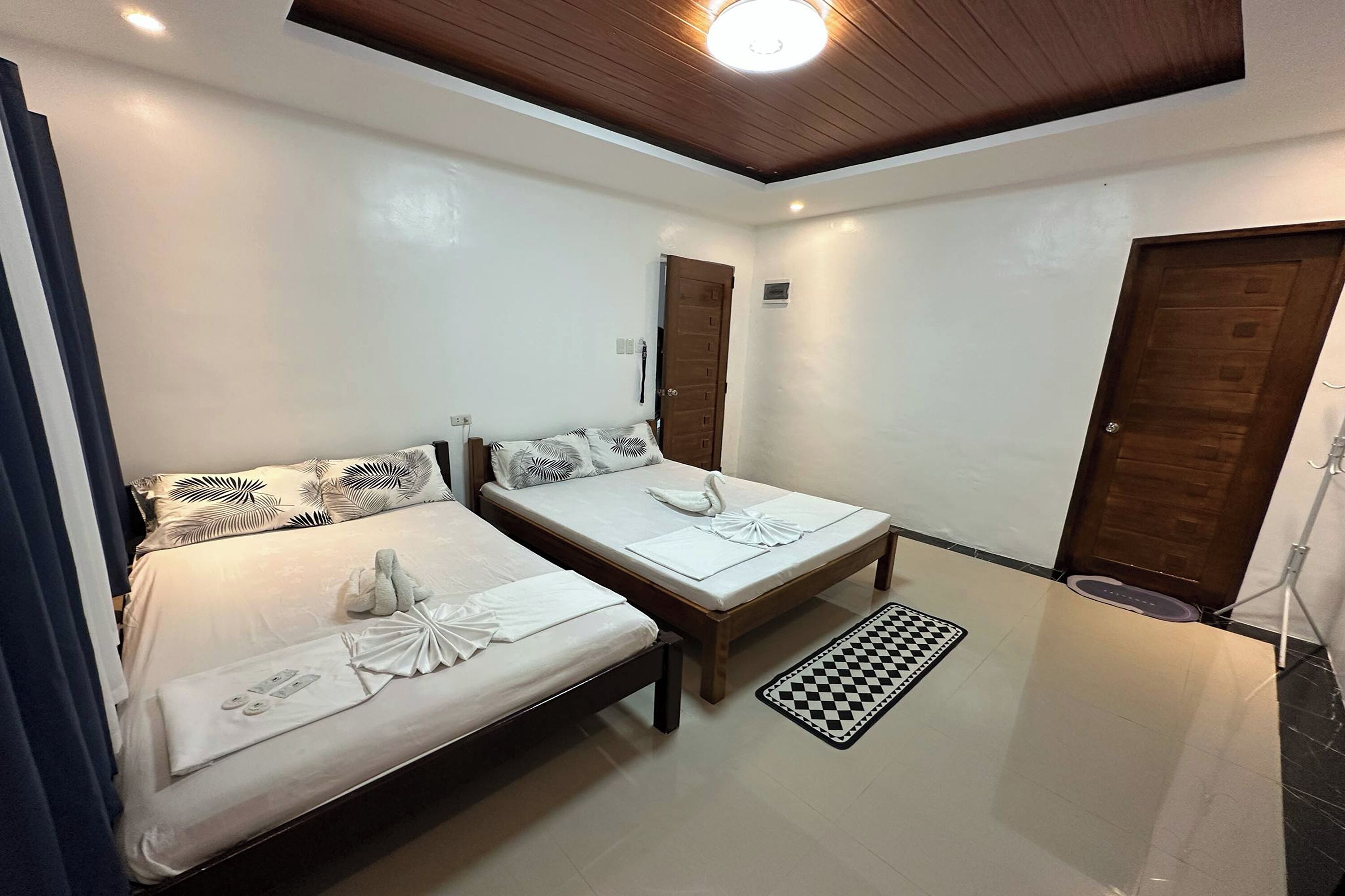 A bedroom with two beds, a checkered mat, and a ceiling light.