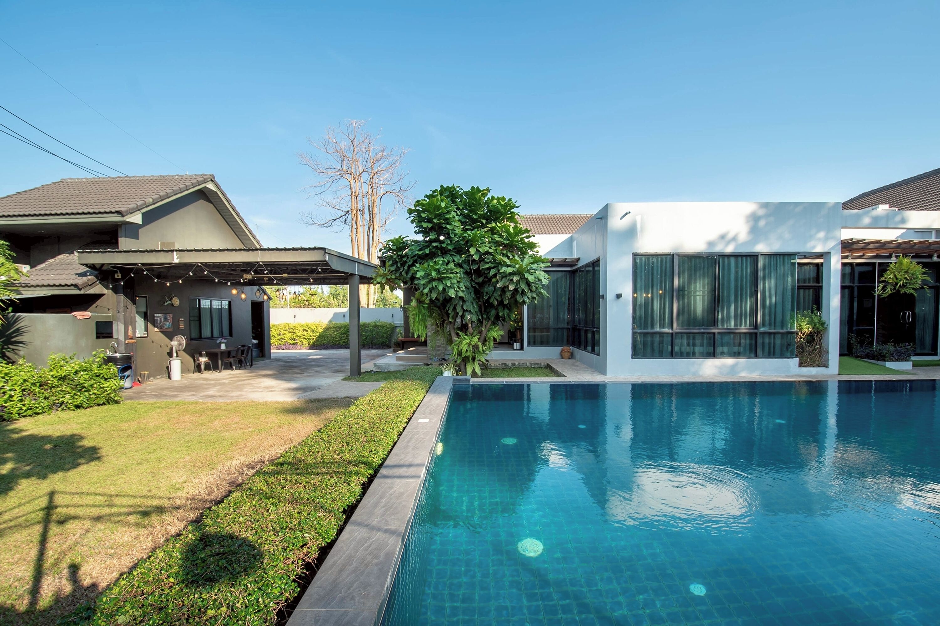 A modern house with a swimming pool, a covered patio, and a well-maintained lawn.