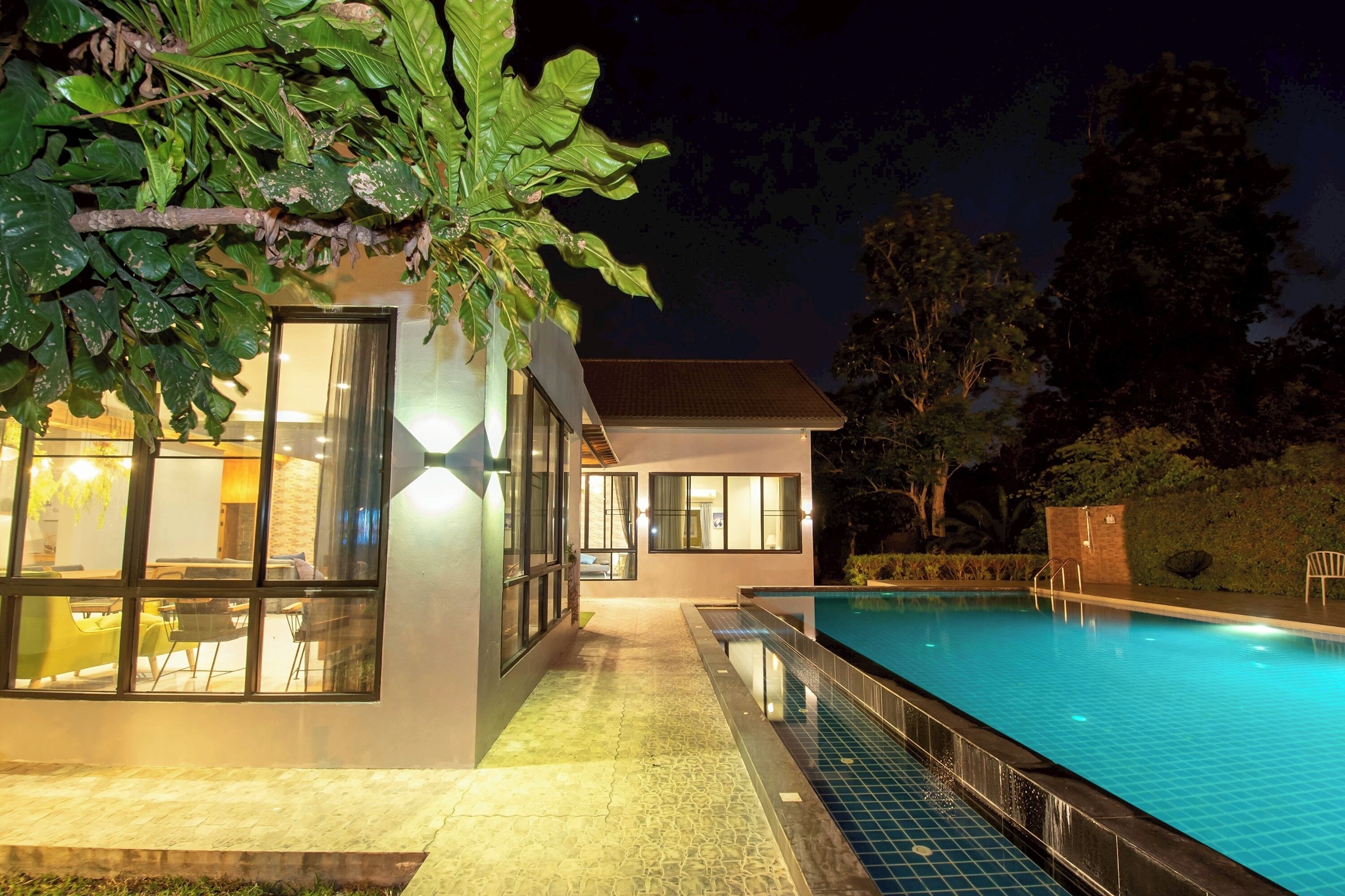 A modern house with a swimming pool, large windows, and a well-lit exterior.