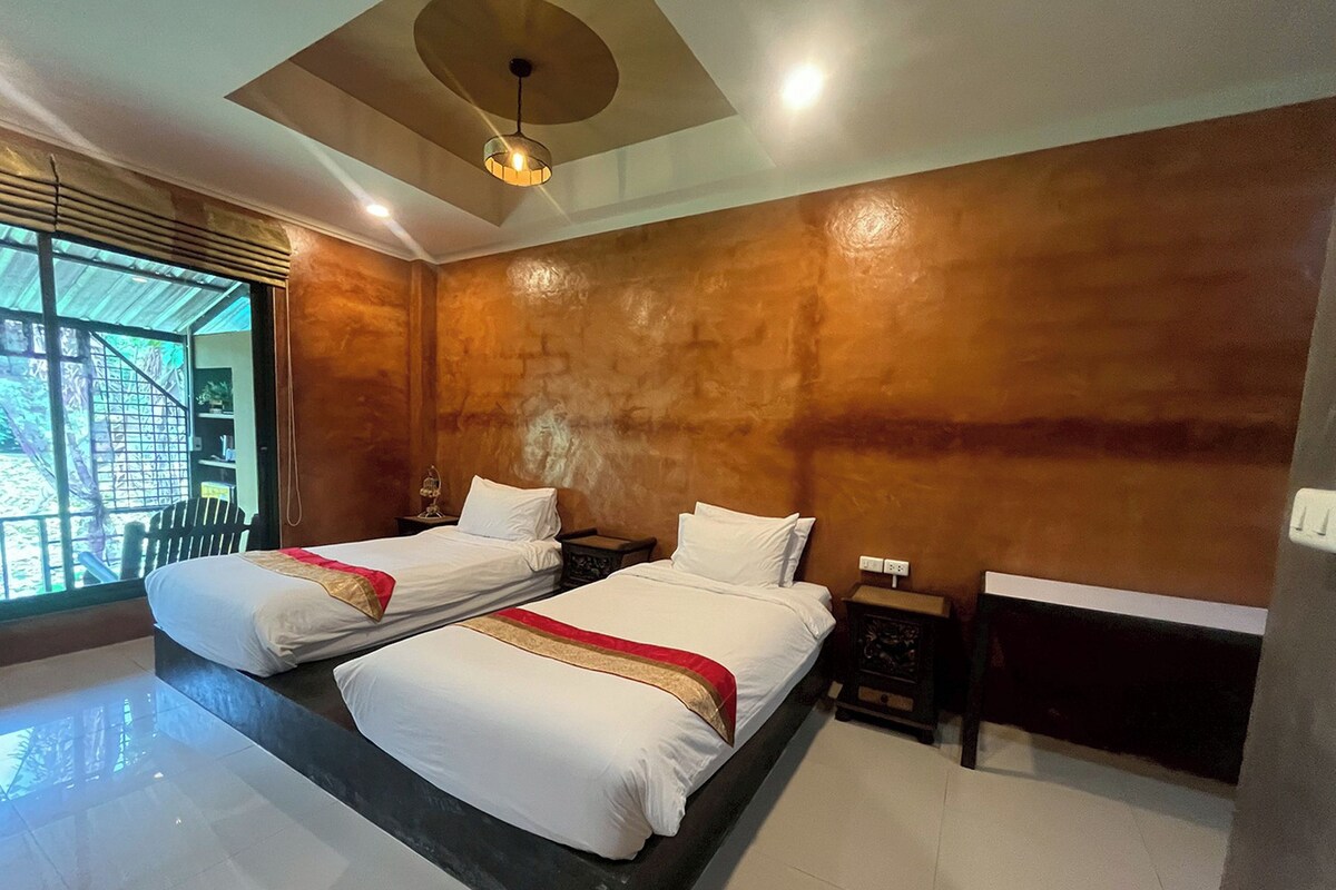 Une chambre d’hôtel moderne avec deux lits, une grande fenêtre et un luminaire au plafond.