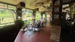 A spacious indoor area with large windows, a wooden floor, and a seating area with tables and chairs. - Saikaew Resort (Chiang Rai)
