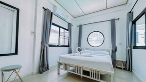Ein modernes Hotelzimmer mit einem großen Bett, einem runden Fenster und einem kleinen Tisch.