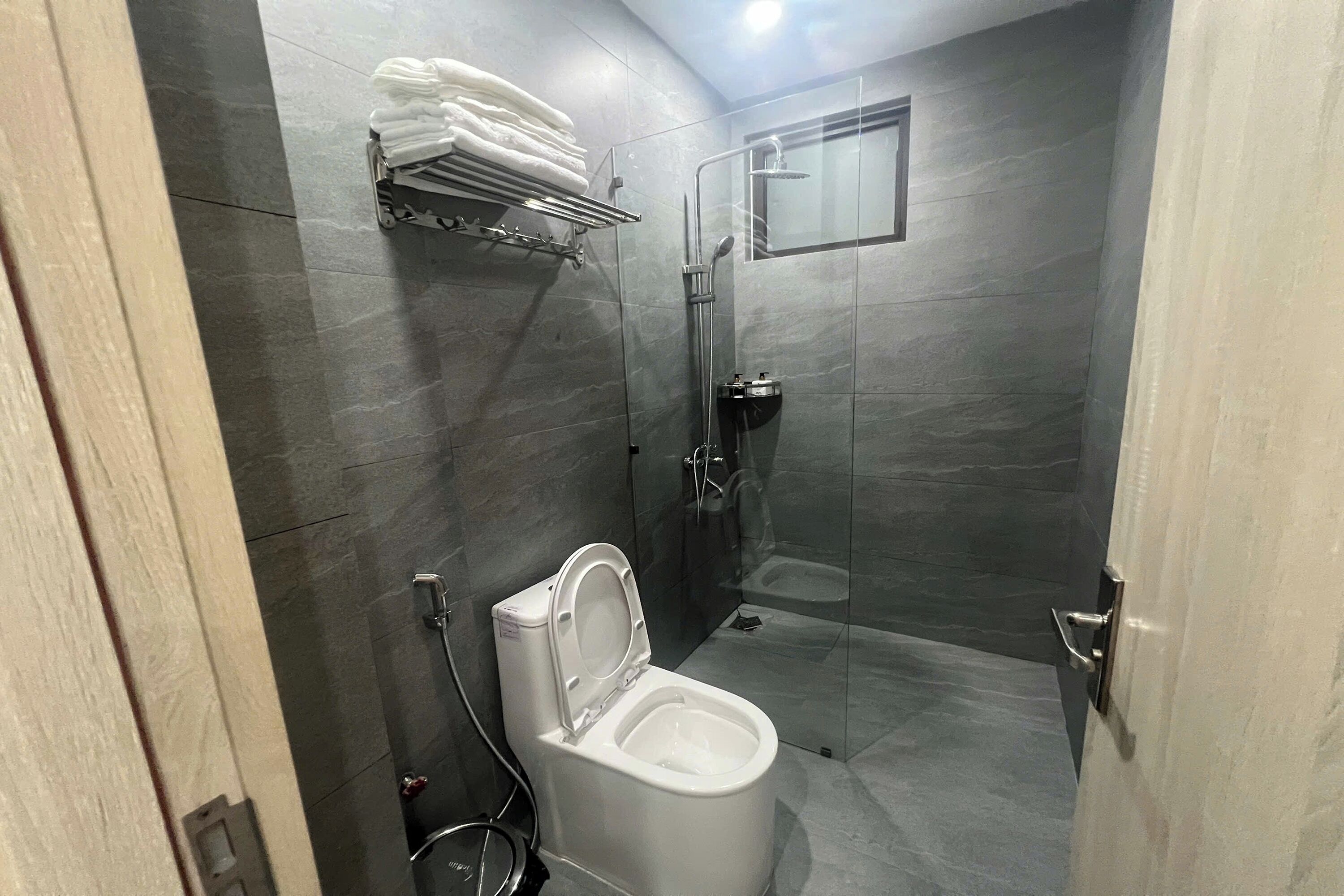 Un baño moderno con inodoro, ducha y cabina de ducha con mampara de vidrio.