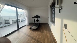 A room with a treadmill, large windows, and a view of the city. - Thao Trang Luxury Hotel Dong Hoi (Dong Hoi)