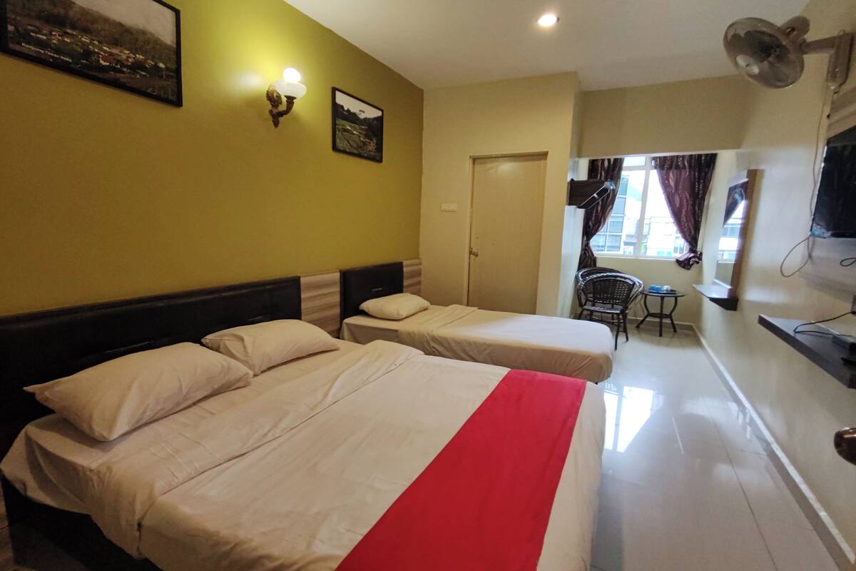 A hotel room with two beds, a desk, a chair, and a TV.