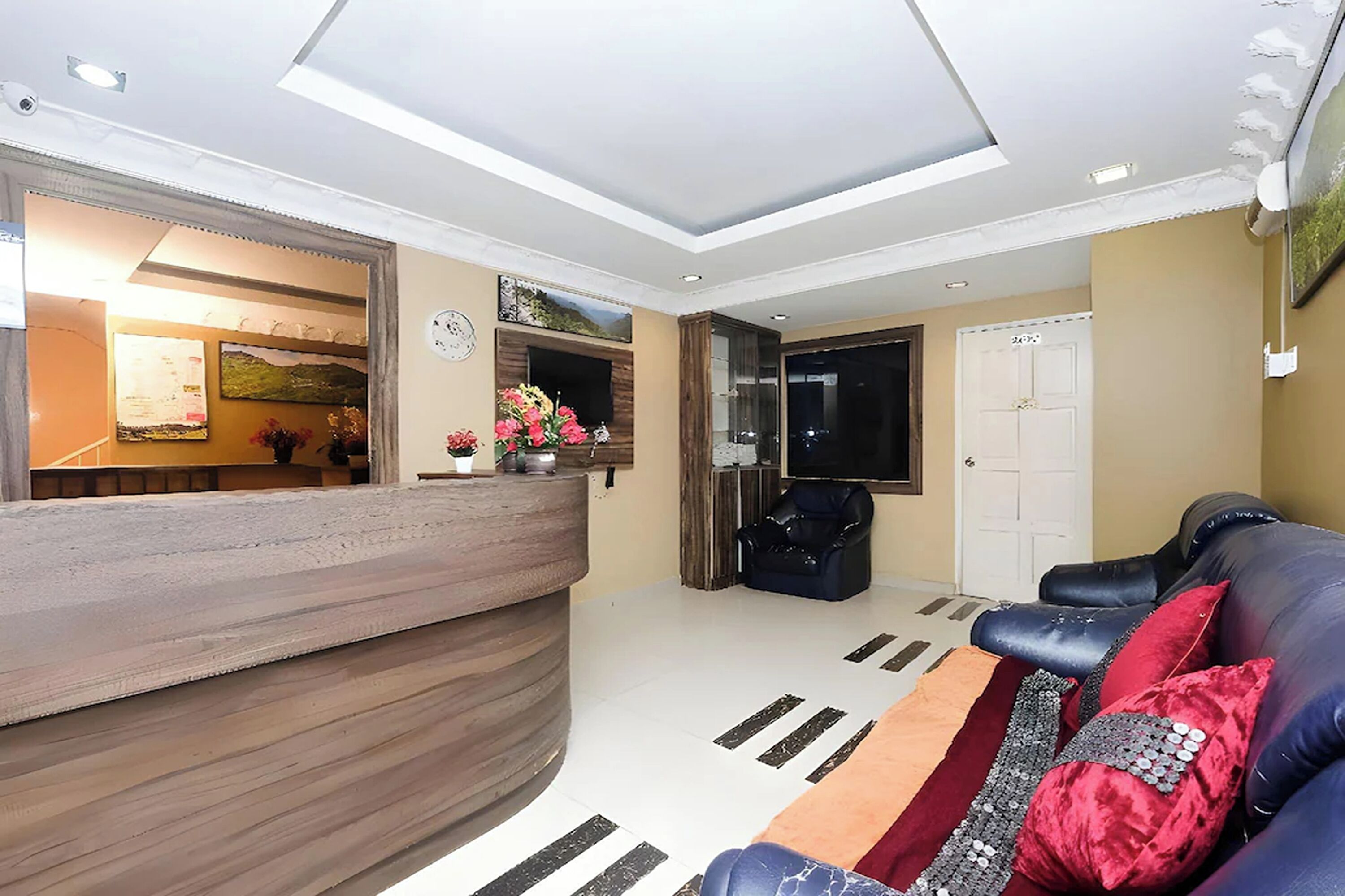 Un'area reception con un bancone in legno, un divano in pelle nera e un cuscino decorativo rosso e argento.