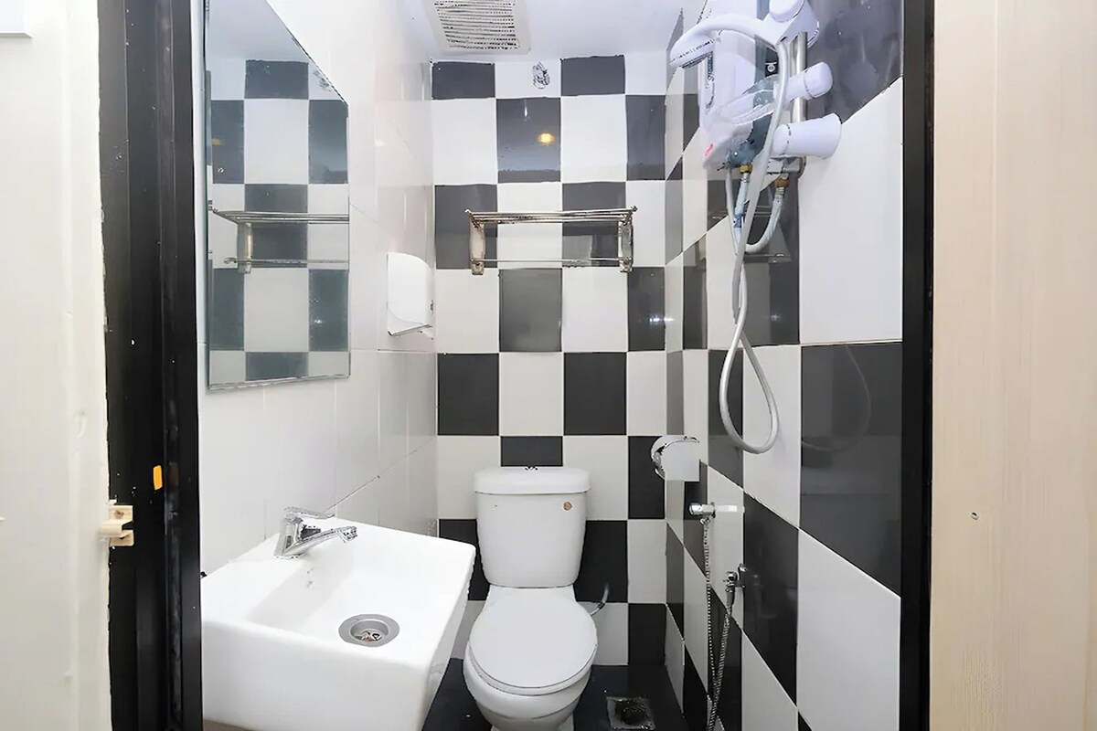 A compact bathroom with a white sink, toilet, and a shower with a handheld showerhead.