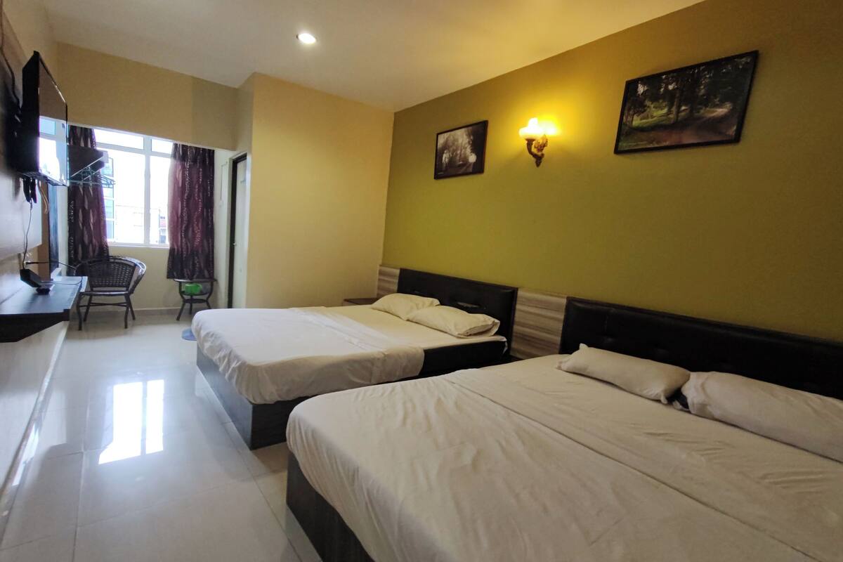 A hotel room with two beds, a desk, a chair, and a window with curtains.