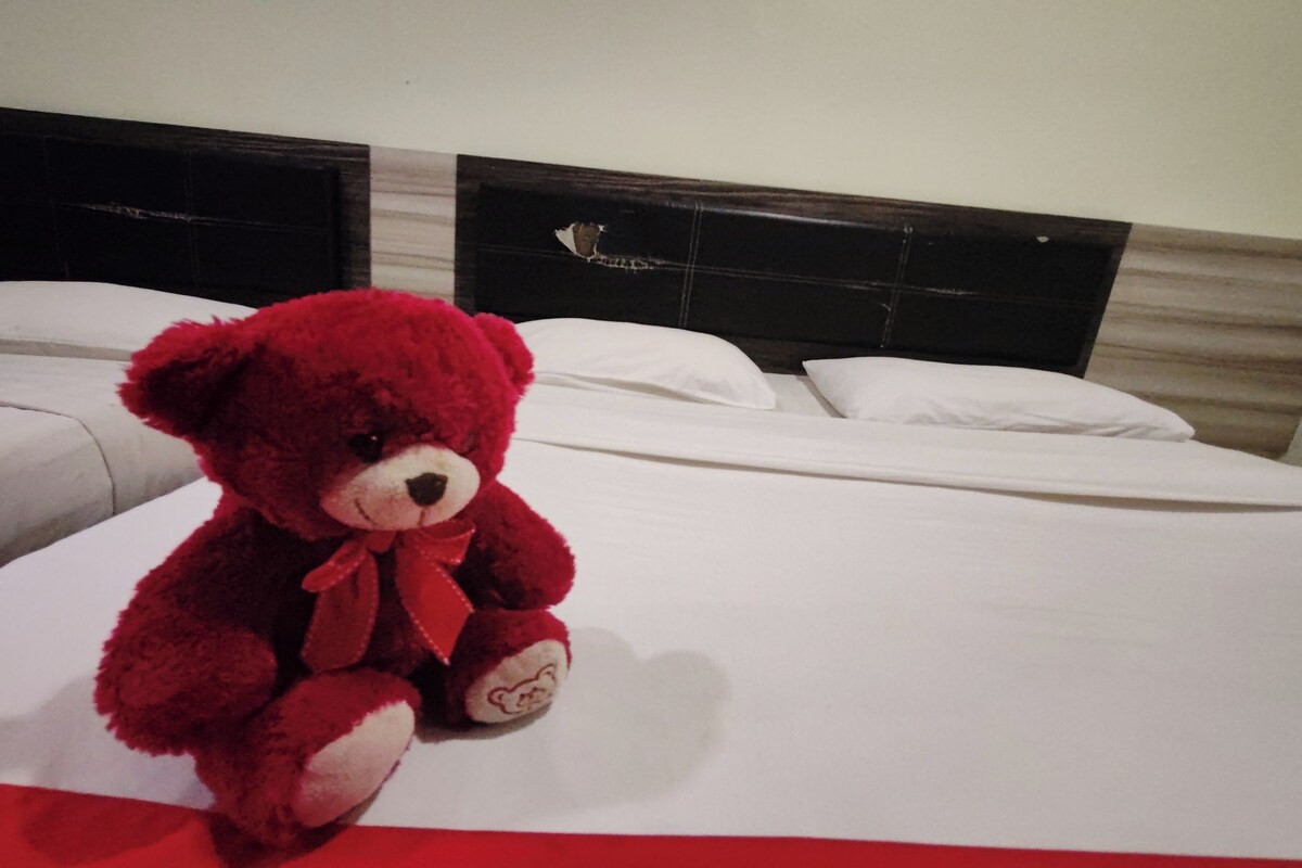 A bed with a red teddy bear on it.