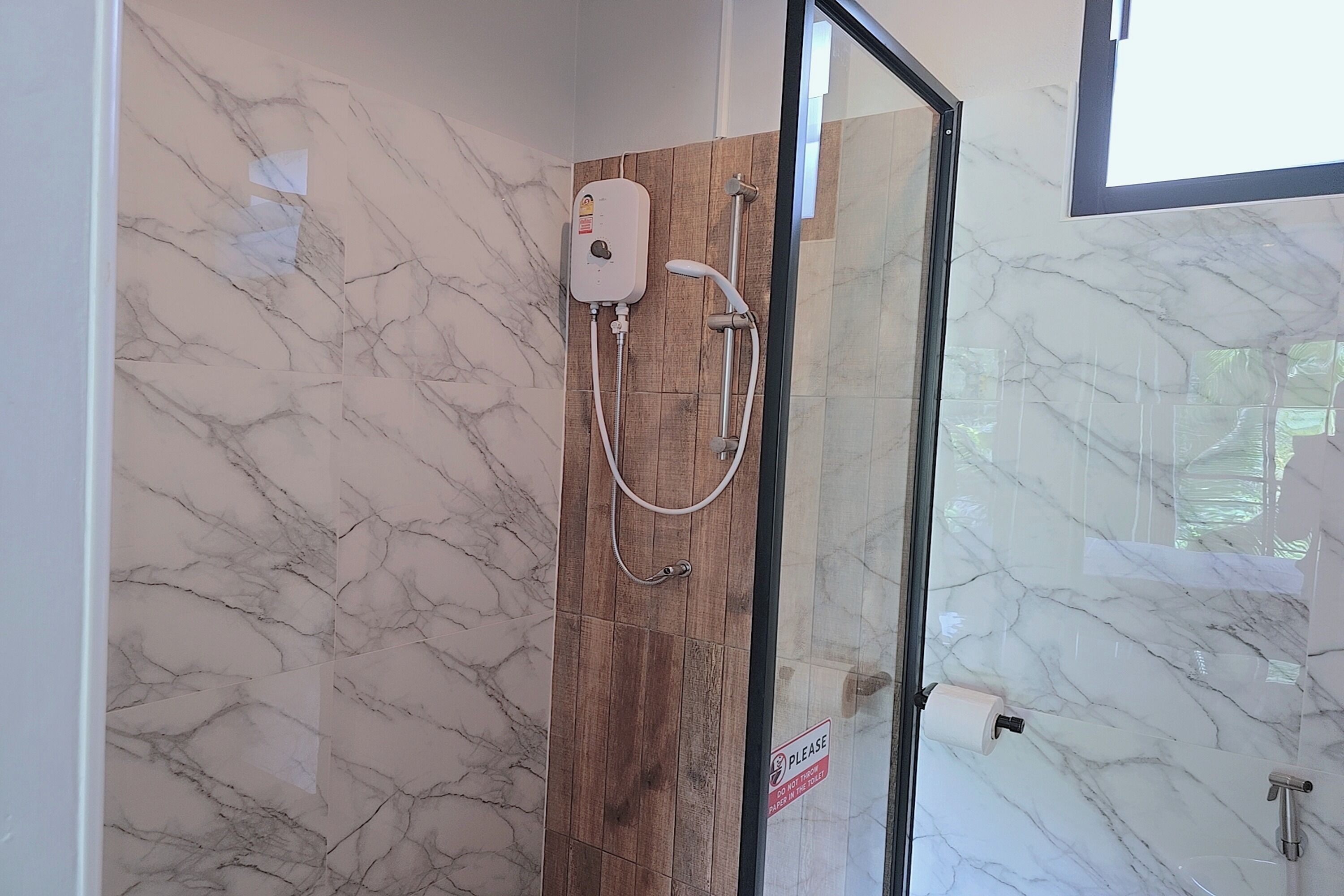 A shower with a control panel, a handheld showerhead, and a glass door.