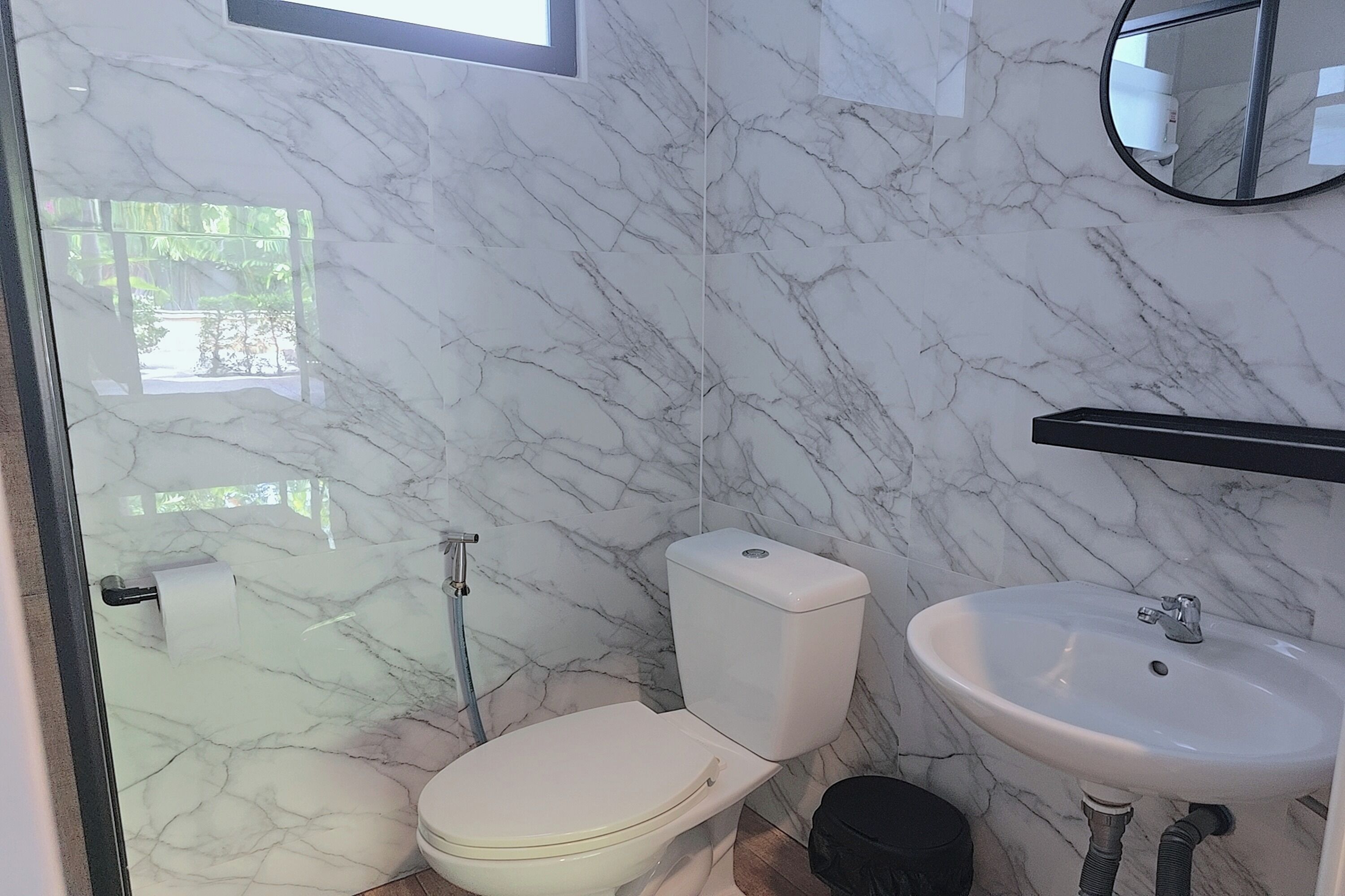 A bathroom with a toilet, sink, and a mirror.
