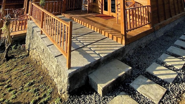 A wooden cabin with a porch, steps, and a fenced area. - Munduk Terrace (Munduk)