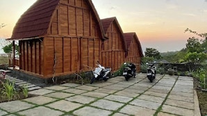 A wooden barn-style building with a paved driveway and parked scooters. - Munduk Terrace (Munduk)