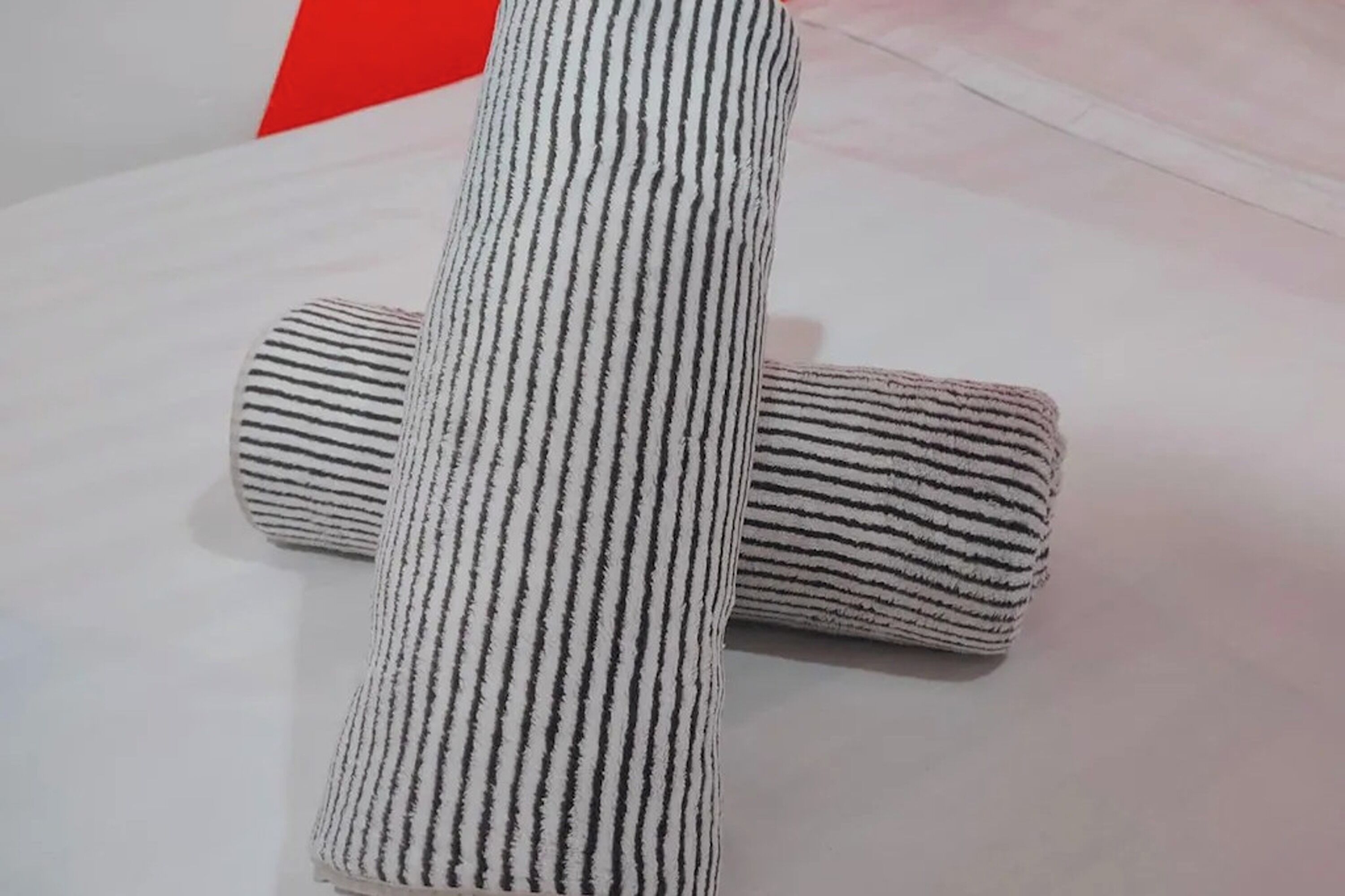 A white pillow with black stripes on a white surface.